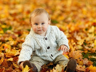 Niño sentado en hojas marrones explorando el entorno